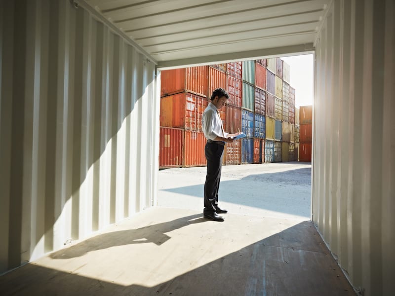 business man standing in an empty shipping container
